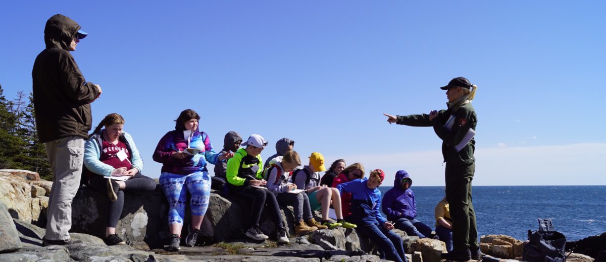 A National Park Student ranger instructs students on the rocks at Schoodic Point