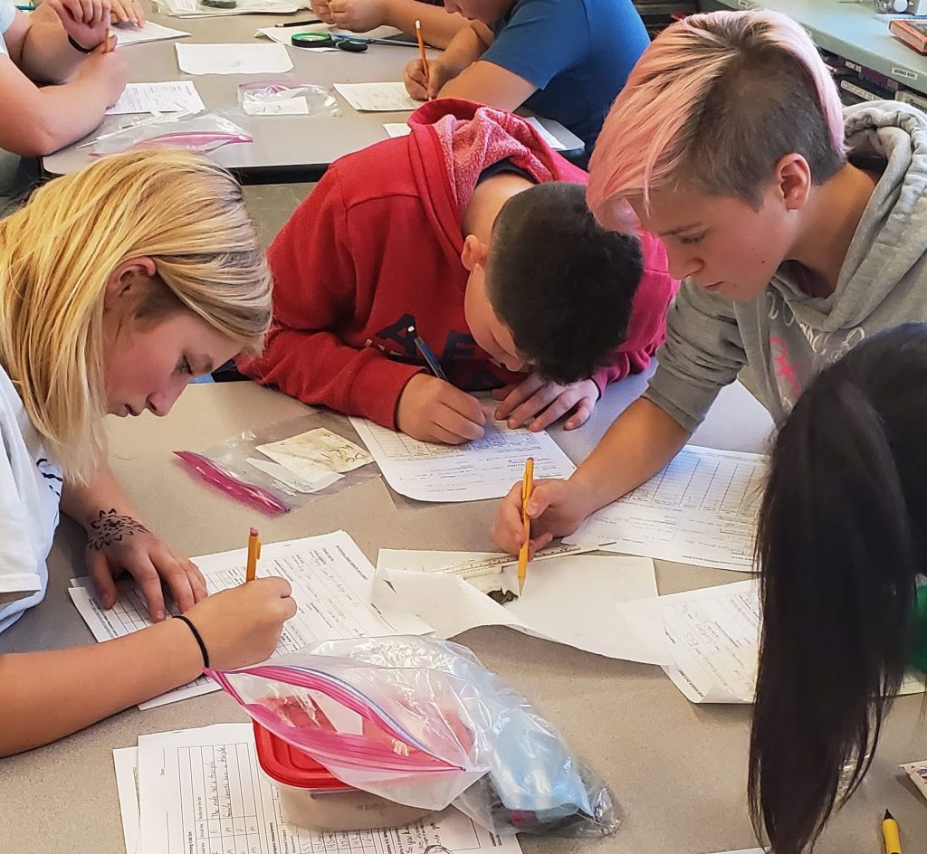 three students filling out worksheets