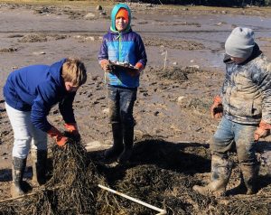 three children stand on the mud