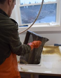 A student washing mud from sampling box at a sink