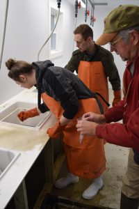 Students at sink in orange rubber aprons