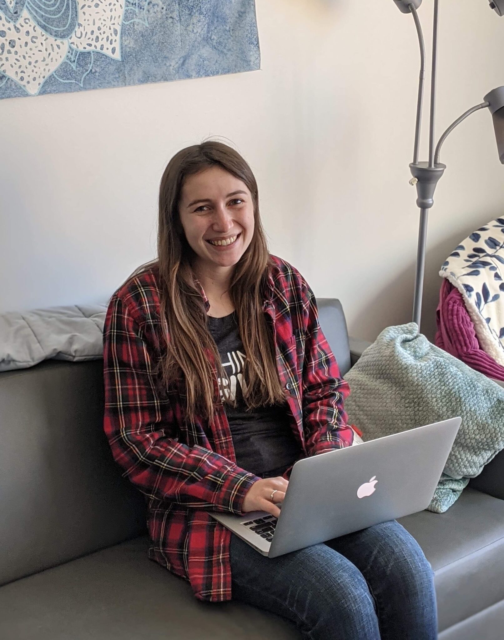 A smiling Tessa Houston sitting on a couch with a laptop.