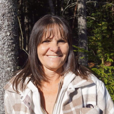 Photo of Bonnie Alvarez, smiling at the camera with tree in background.