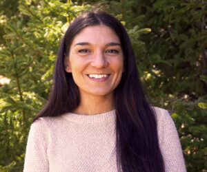 Headshot of Sarah Luchini, facing camera smiling with trees in background.