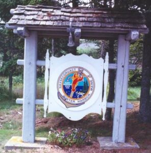 Front gate sign of former navy base, trees in background