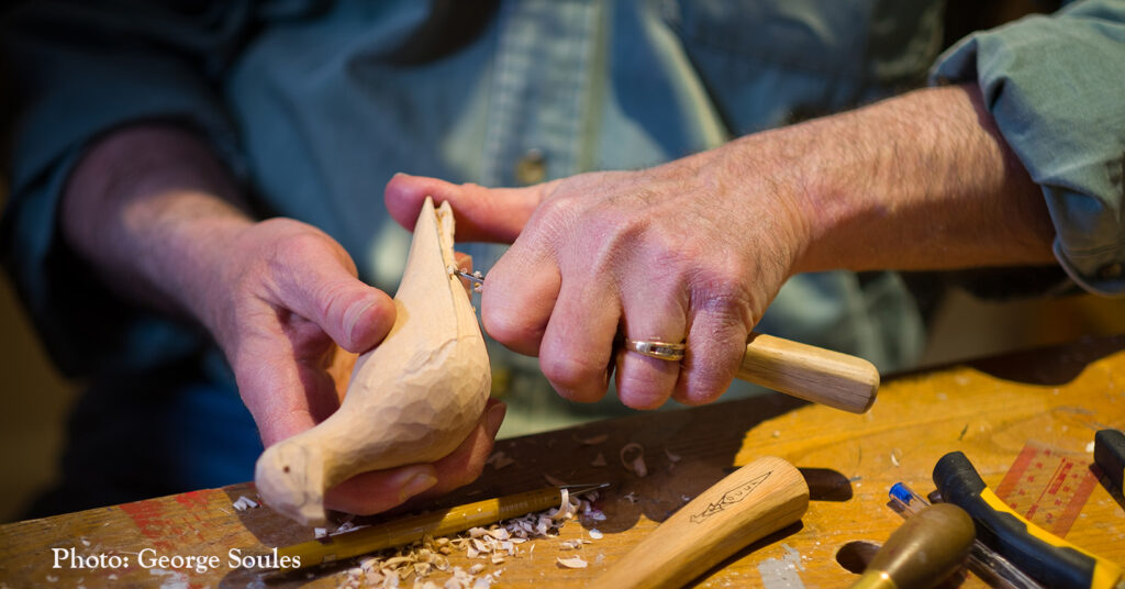 close up of hands carving a bird out of wood