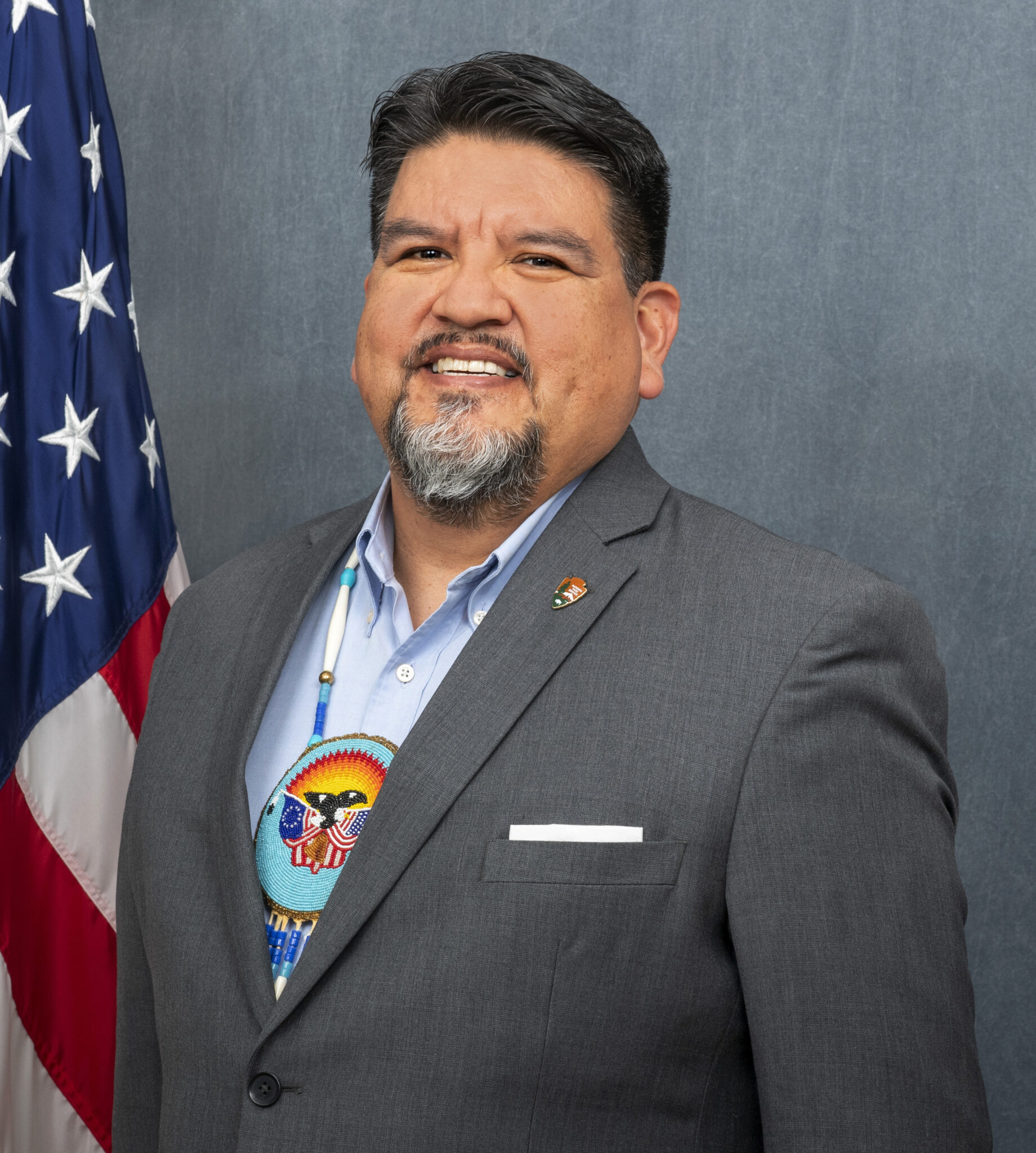 Headshot of Chuck Sams, American flag in background