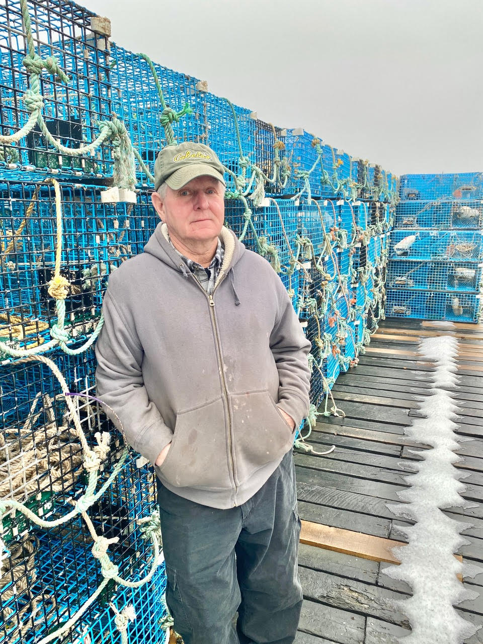 Person leaning against lobster crates on wooden dockdock