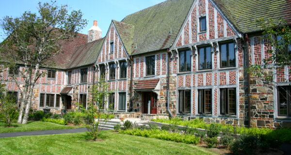 View of Rockefeller Hall on the Schoodic Institute campus. Green grass is shown in the foreground, and in the background is a bright blue sky.