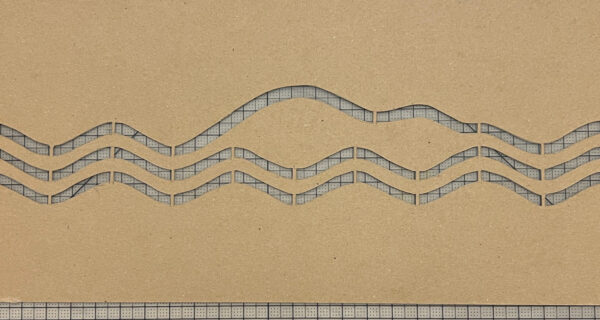 cardboard stencil of three wavy lines. the top line mirrors the profile of Mount Desert Island