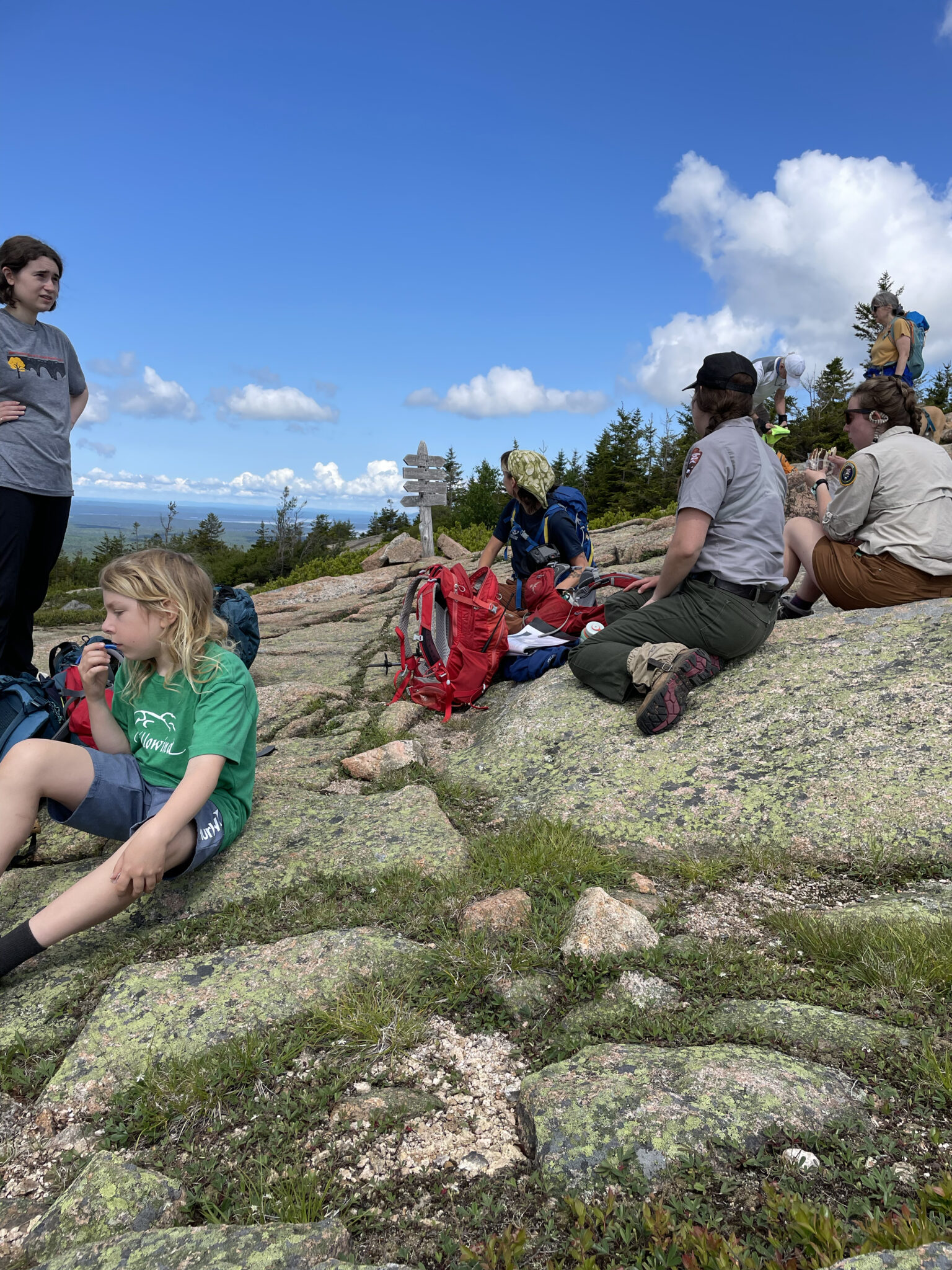 Volunteers and researchers sit at the summit of a mountain in Acadia National Park after lugging soil to the top. 