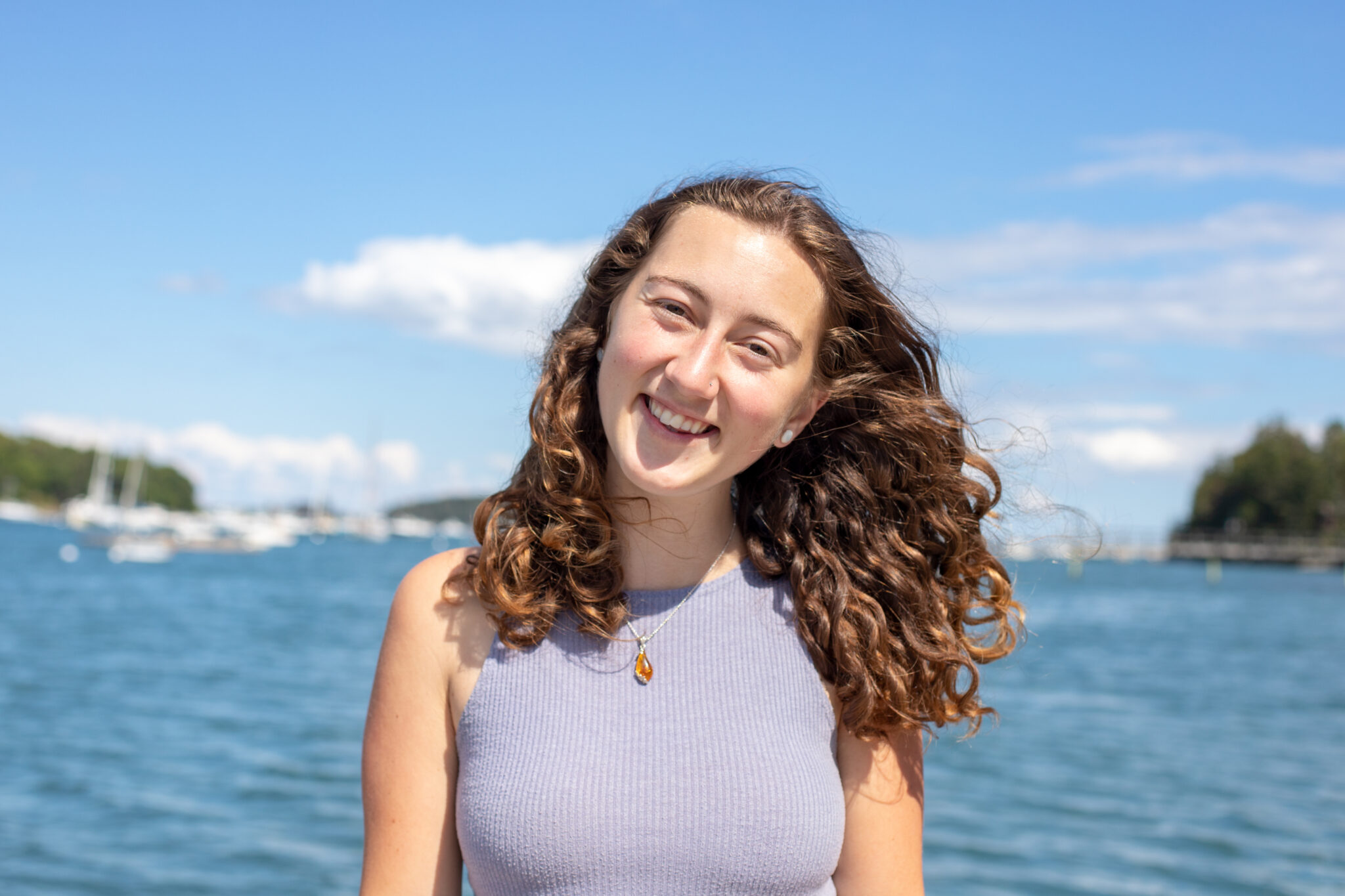Headshot of Brianna Cunliffe, smiling at the camera with the ocean in background under a bright sky.