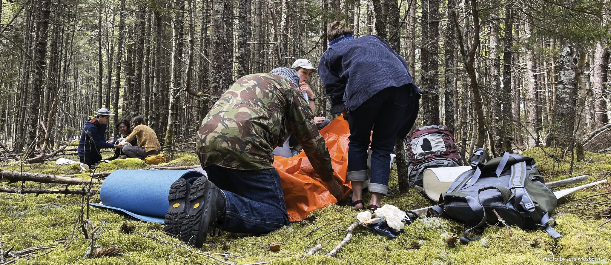 Participants in a Wilderness First Aid (WFA) course hone their emergency response skills in a simulated emergency scenario in the woods.