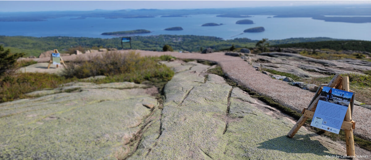 View from the summit of Cadillac Mountain in Acadia National Park on a bright day, looking outward toward the ocean beyond.