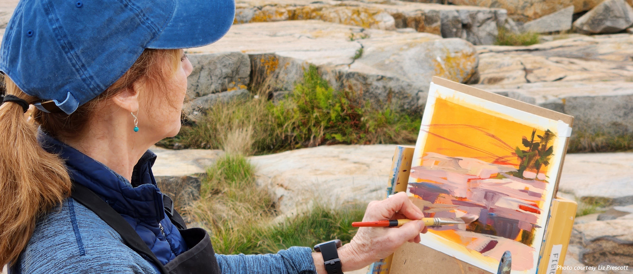 Artist Liz Prescott paints outdoors on the rocks along the Schoodic Peninsula coastline.