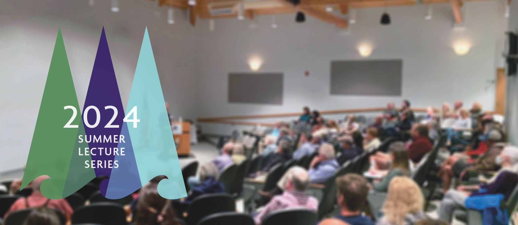 A crowded auditorium at Schoodic Institute listens to a presenter, standing at a podium. Overlaid is the Schoodic Institute logo artwork, depicting a stylized re-imagining of trees and ocean waves, with text that reads: 2024 Summer Lecture Series.