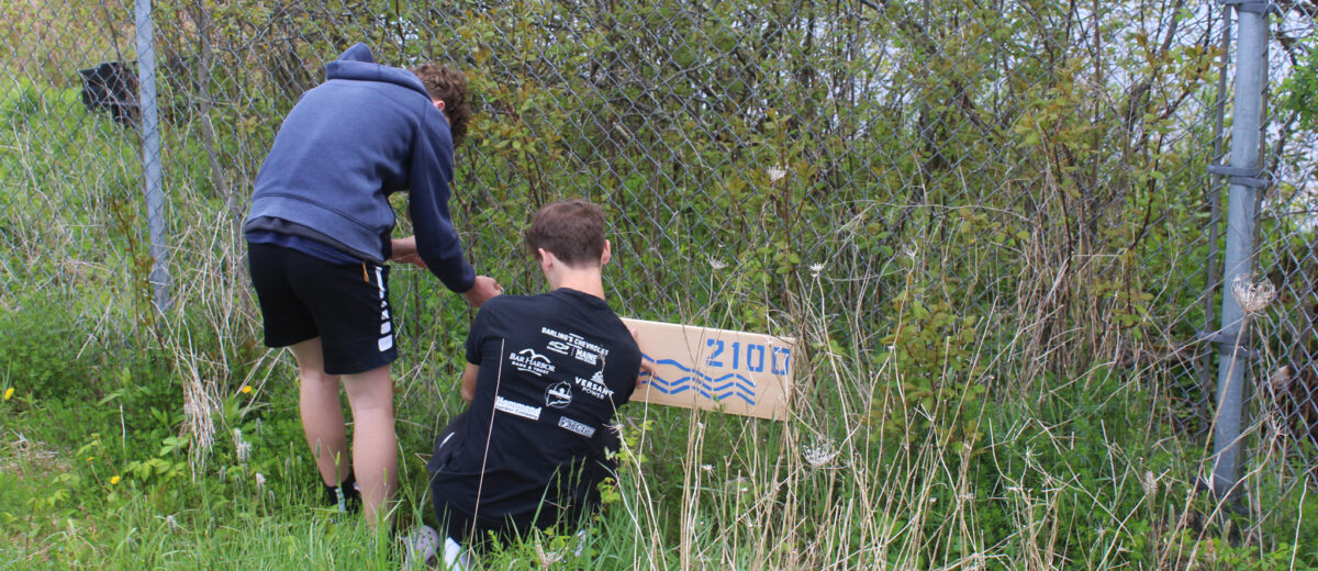 Two young students put up a sign to help visualize the projected future sea level rise.