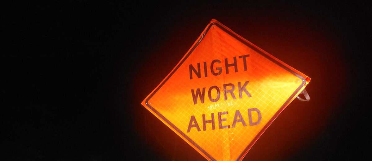 A nighttime view of a road sign that reads, Night Work Ahead