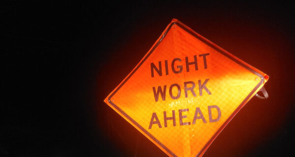 A nighttime view of a road sign that reads, Night Work Ahead