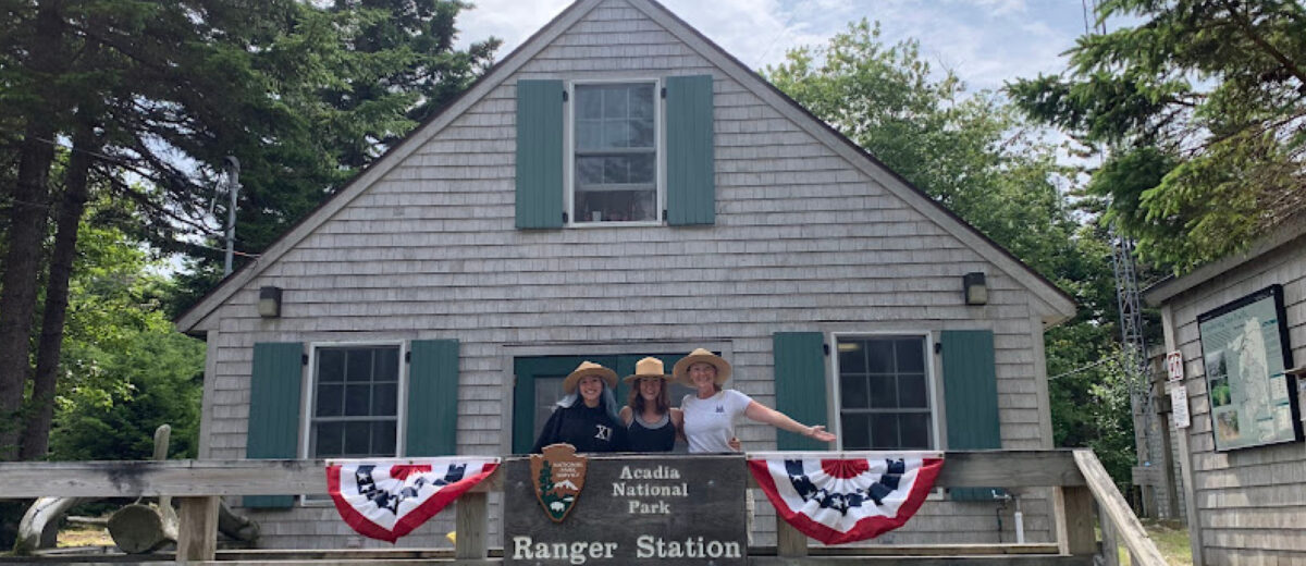 Three members of the 2024 Forest Health Monitoring Crew pose for a photo on the porch of the Isle au Haut Ranger Station