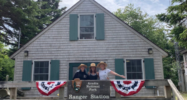 Three members of the 2024 Forest Health Monitoring Crew pose for a photo on the porch of the Isle au Haut Ranger Station