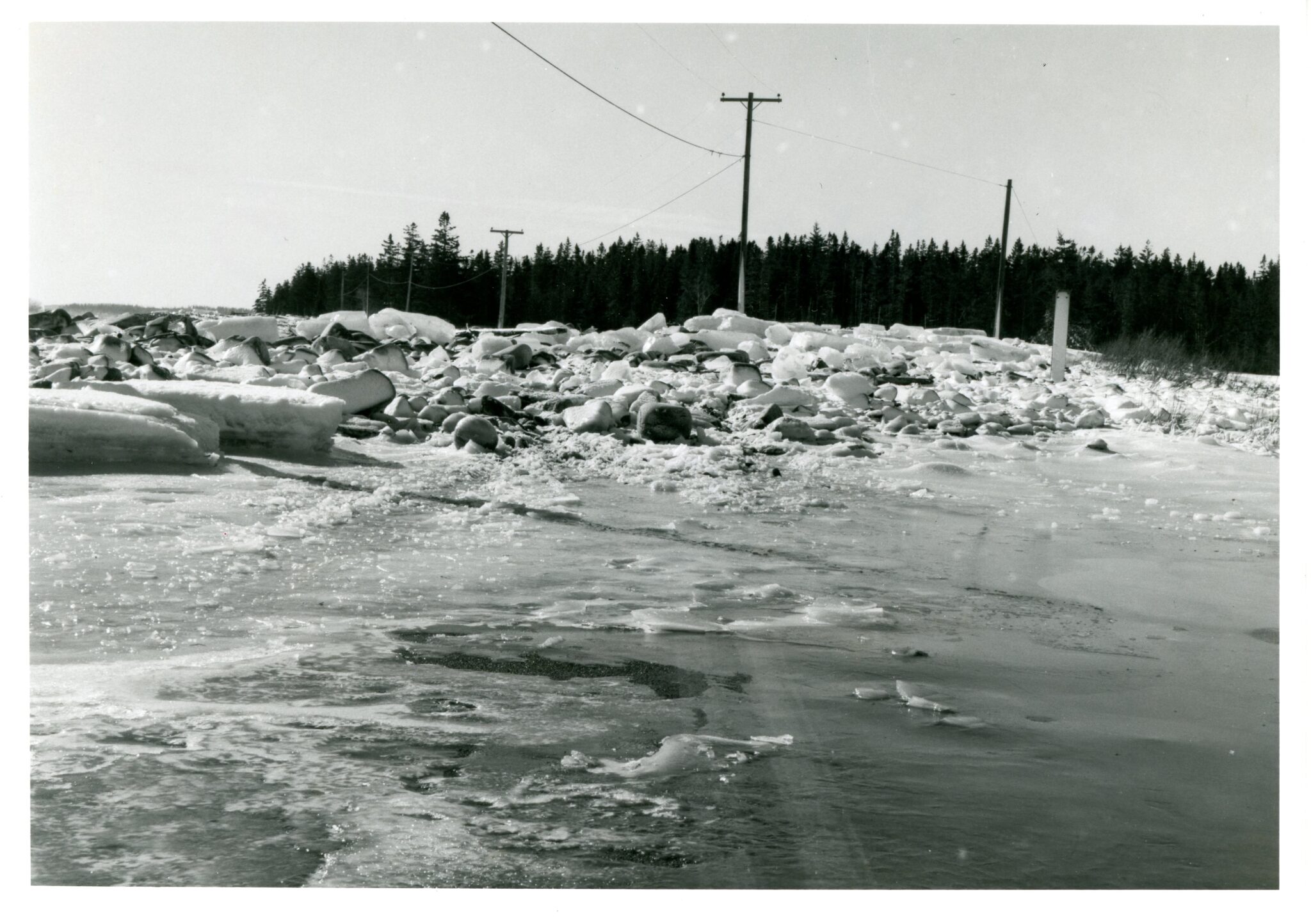 An undated photograph by LaRue Spiker shows snow and ice-encrusted rocks strewn over the Seawall Road.