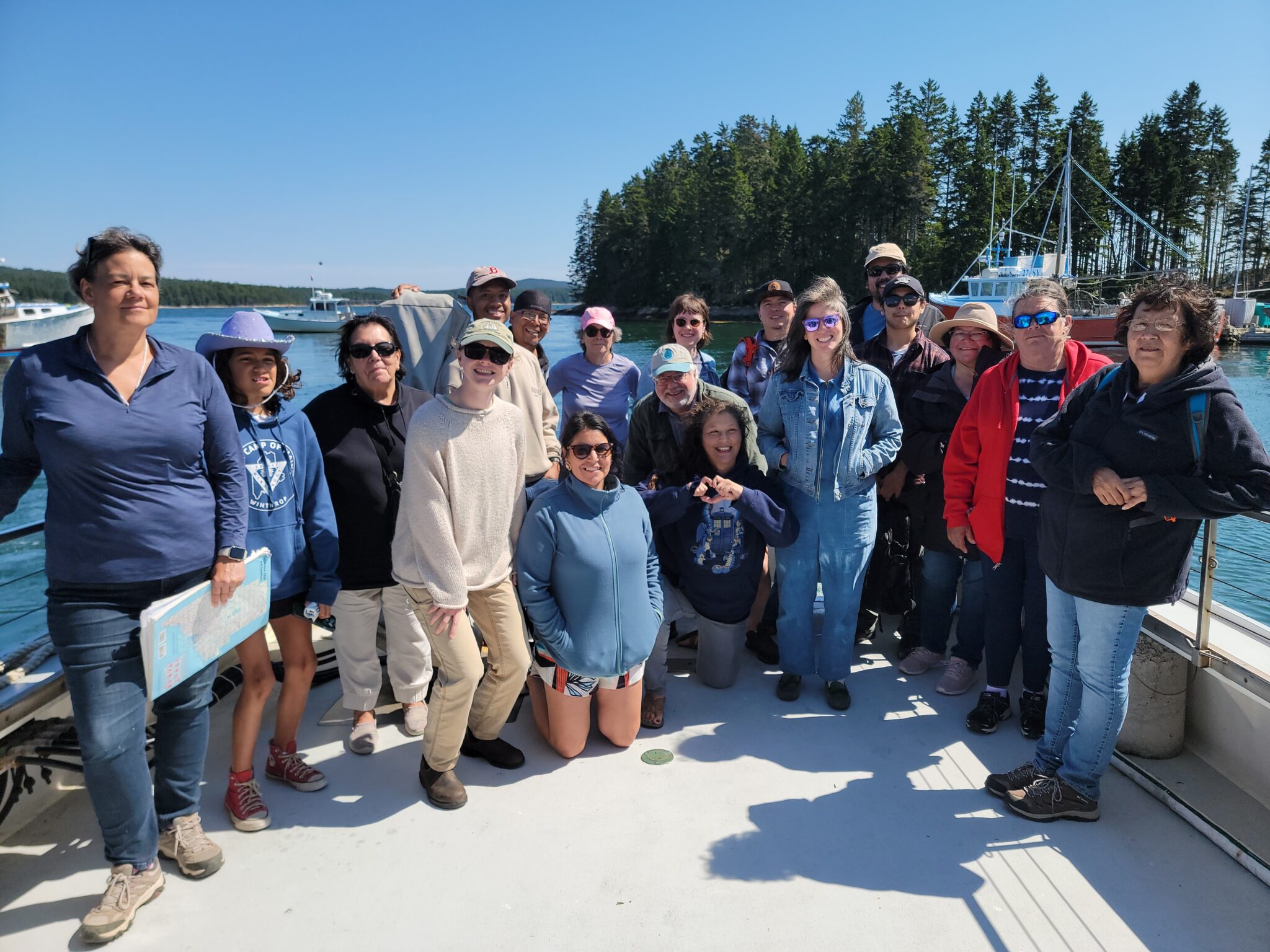 Beneath a clear blue sky, a large group gathers together aboard the "Osprey", a research vessel from College of the Atlantic