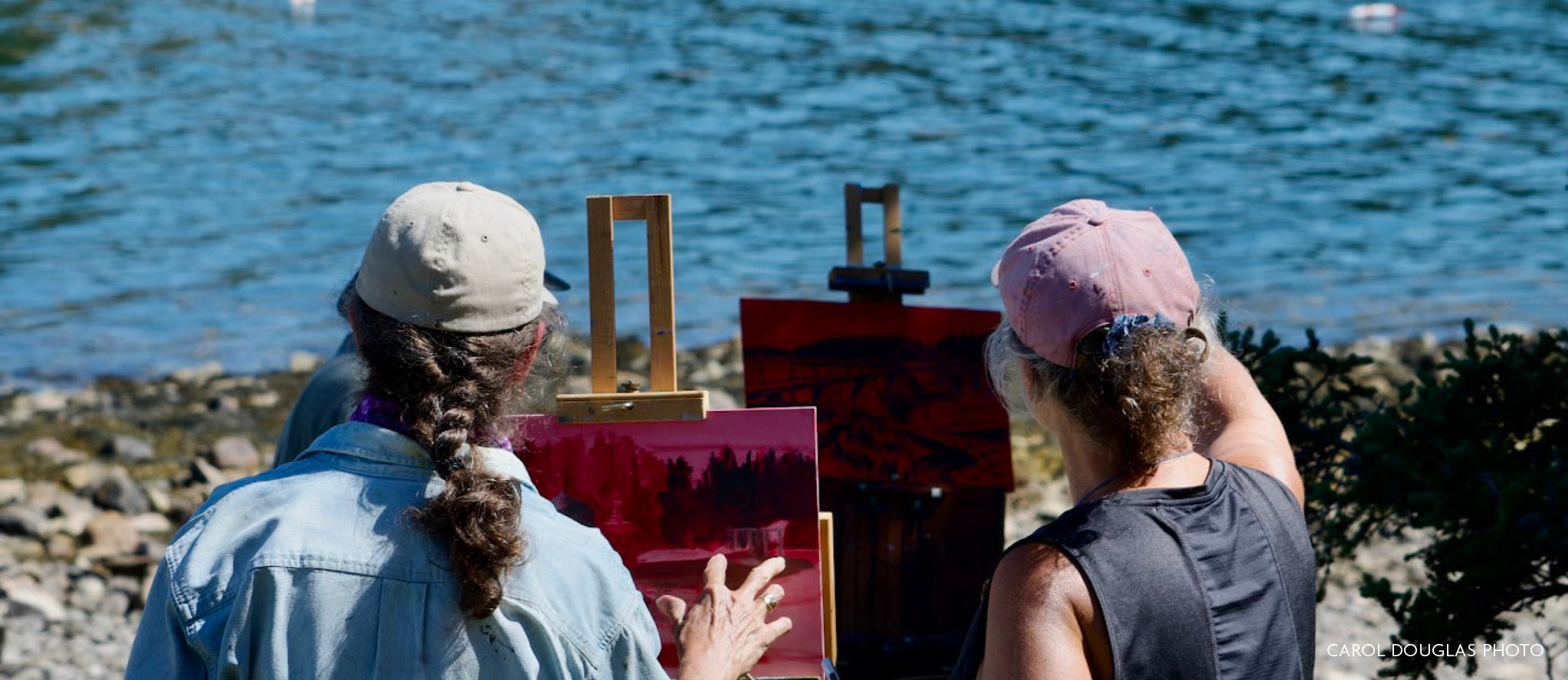 Two painters stand at their easels, facing the ocean, while planning their compositions and analyzing the outdoor light