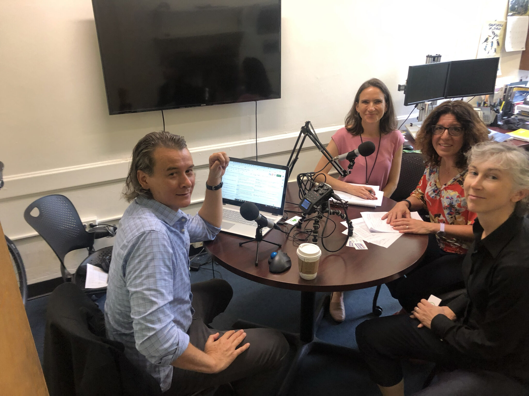 Doug Parsons, Director of America Adapts Media and host of America Adapts – The Climate Change Podcast, sits at a table with podcast equipment as he records a conversation with three guests
