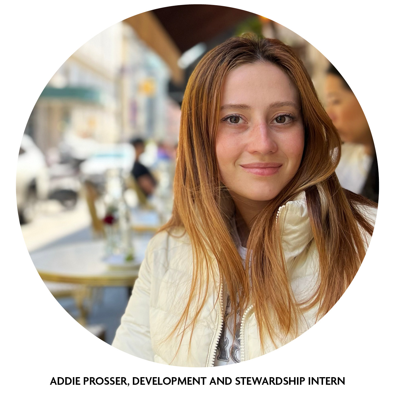 Addie smiles for a photo while sitting outdoors at a cafe